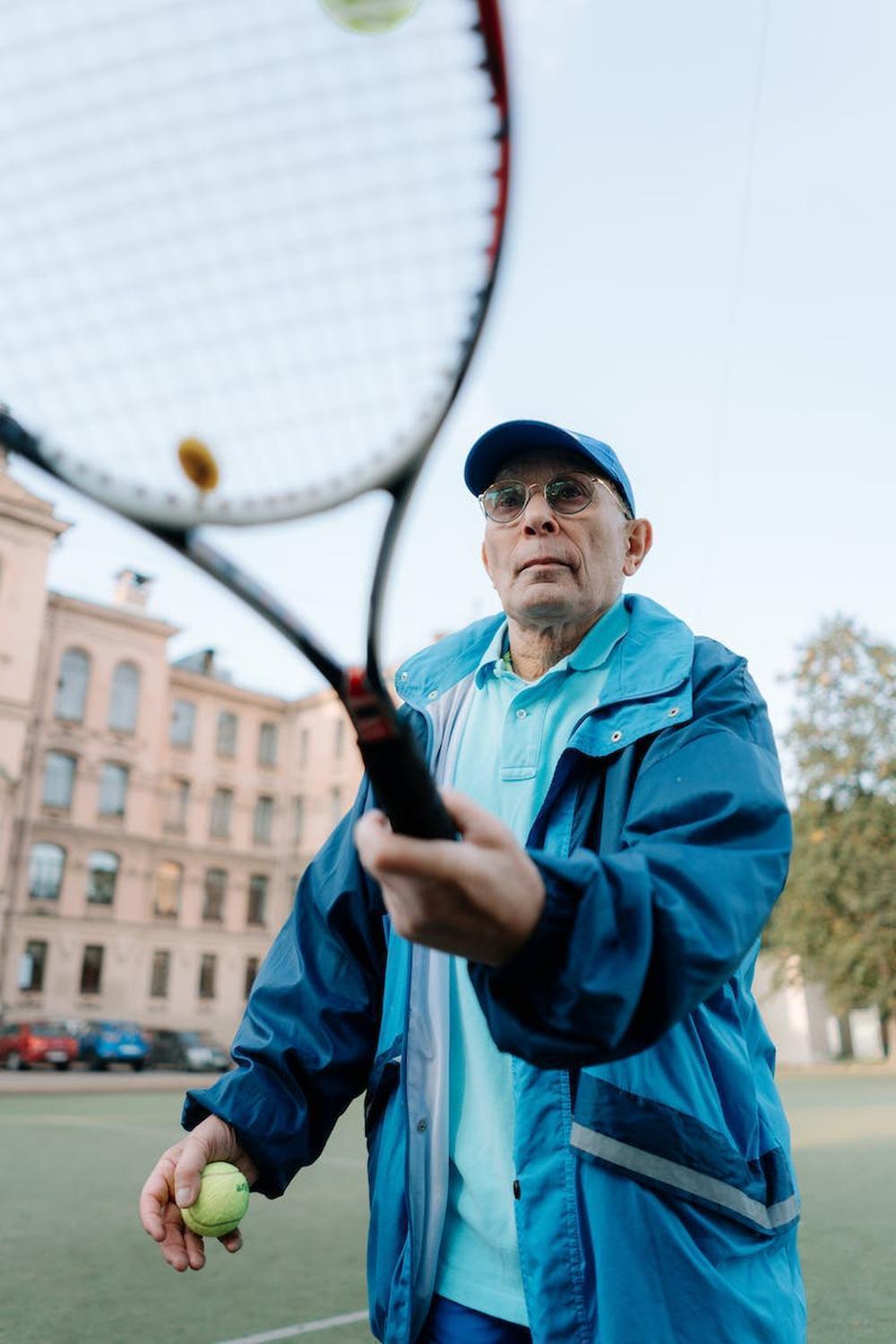 adult_man_in_blue_jacket_holding_a_tennis_racket_a